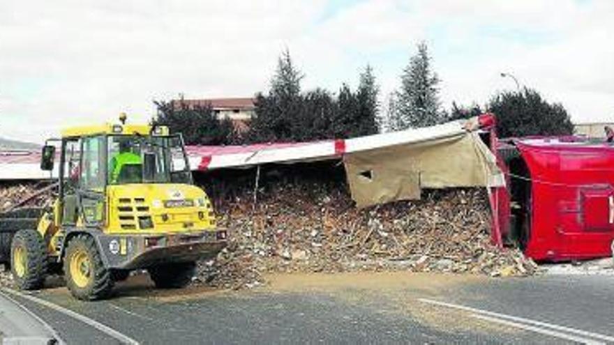 Una excavadora recoge los escombros que portaba el camión volcado en la rotonda de Talluntxe.