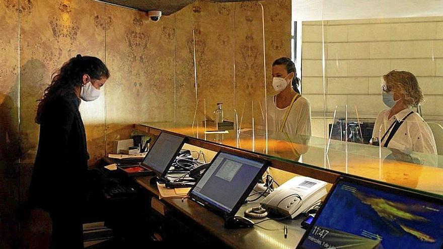 Una recepcionista atiende a dos clientes en un hotel. Foto: Efe Una recepcionista atiende a dos clientes en un hotel. Foto: Efe