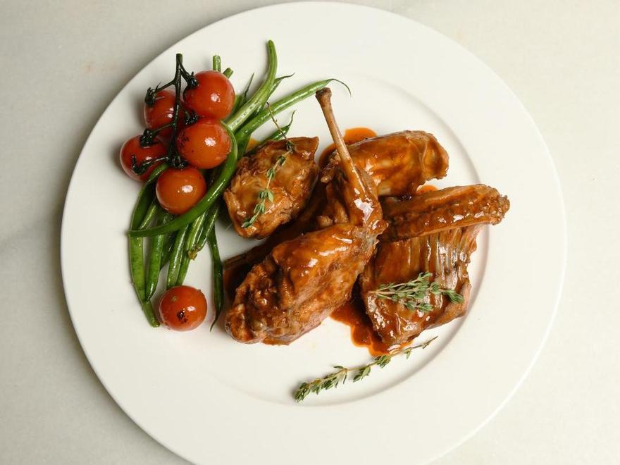 Conejo en adobo con alubia verde y tomates.