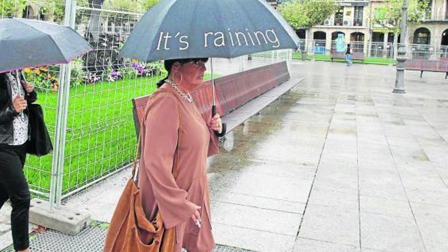 Una mujer pasea bajo la lluvia por la plaza del Castillo.