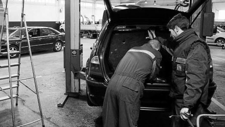 Unos mecánicos arreglan un coche en un taller de reparación en Cordovilla.