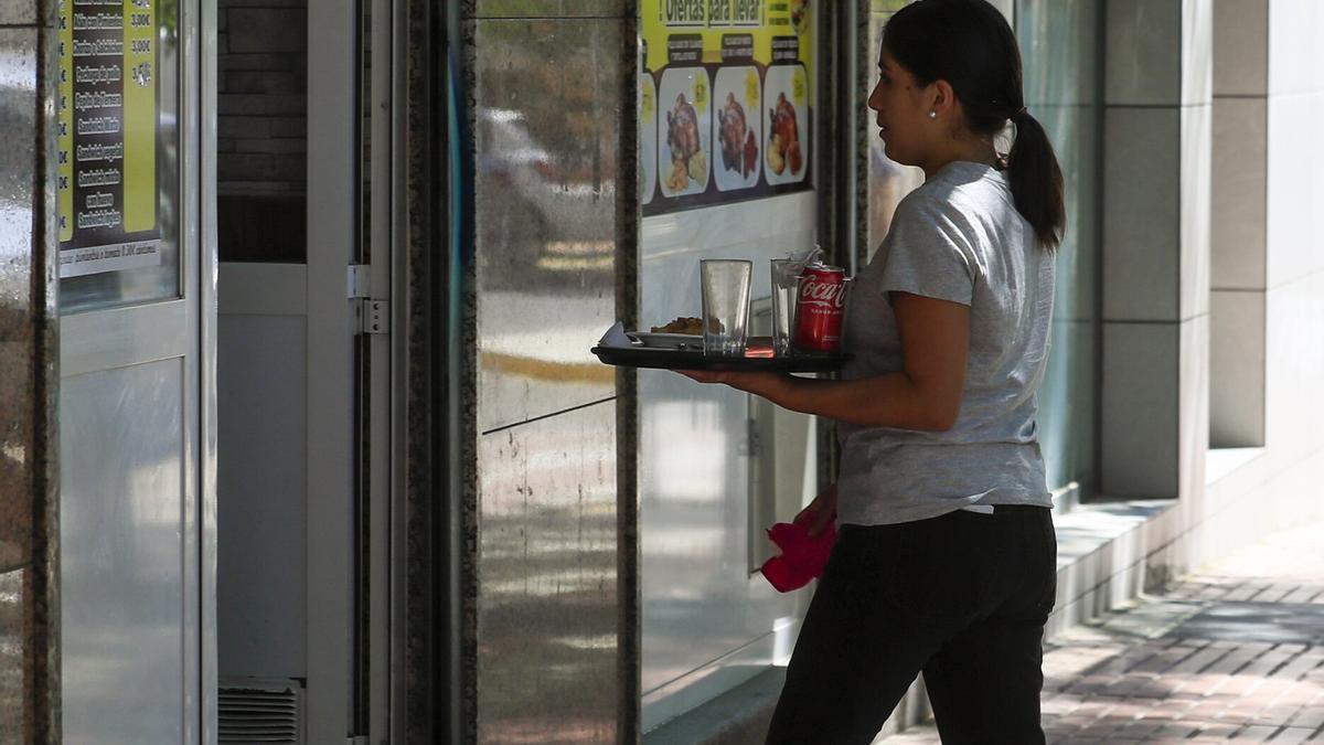 Una camarera retira un servicio en una terraza