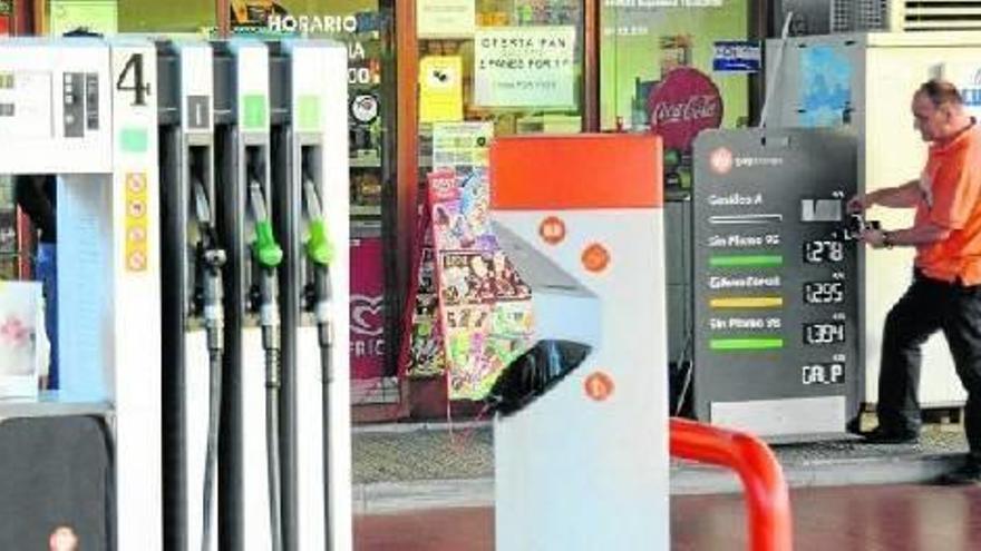 Un trabajador de una gasolinera cambia el panel de precios.