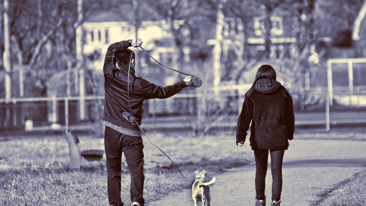 Imagen de archivo de dos personas paseando a su perro.