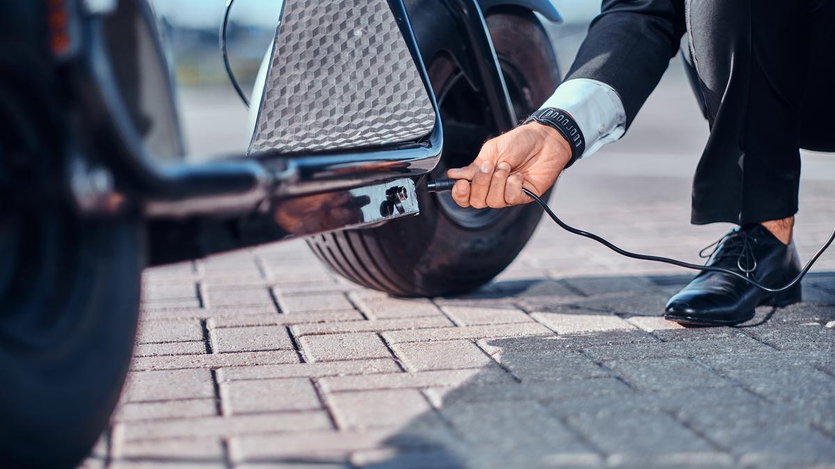 Un hombre carga su patinete eléctrico en un aparcamiento especial.