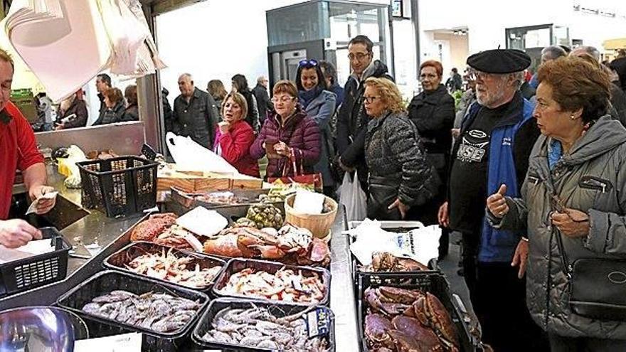 Varias personas realizan sus compras para los menús navideños en uno de los puestos de pescado y marisco de un mercado. Foto: Efe