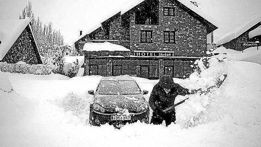 Un hombre intenta desenterrar su coche en Benasque.