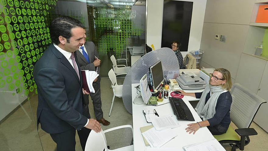 El consejero Alli, acompañado por Oto, conversa con el personal de la oficina del voluntariado.