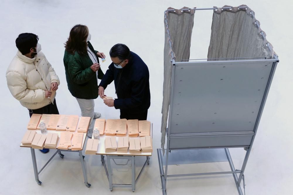 Tres personas preparan su papeleta de votación en un colegio electoral de Valladolid.