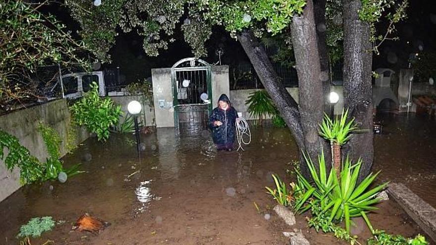 Una mujer camina por el jardín inundado de una casa durante una tormenta en Olbia, isla de Cerdeña