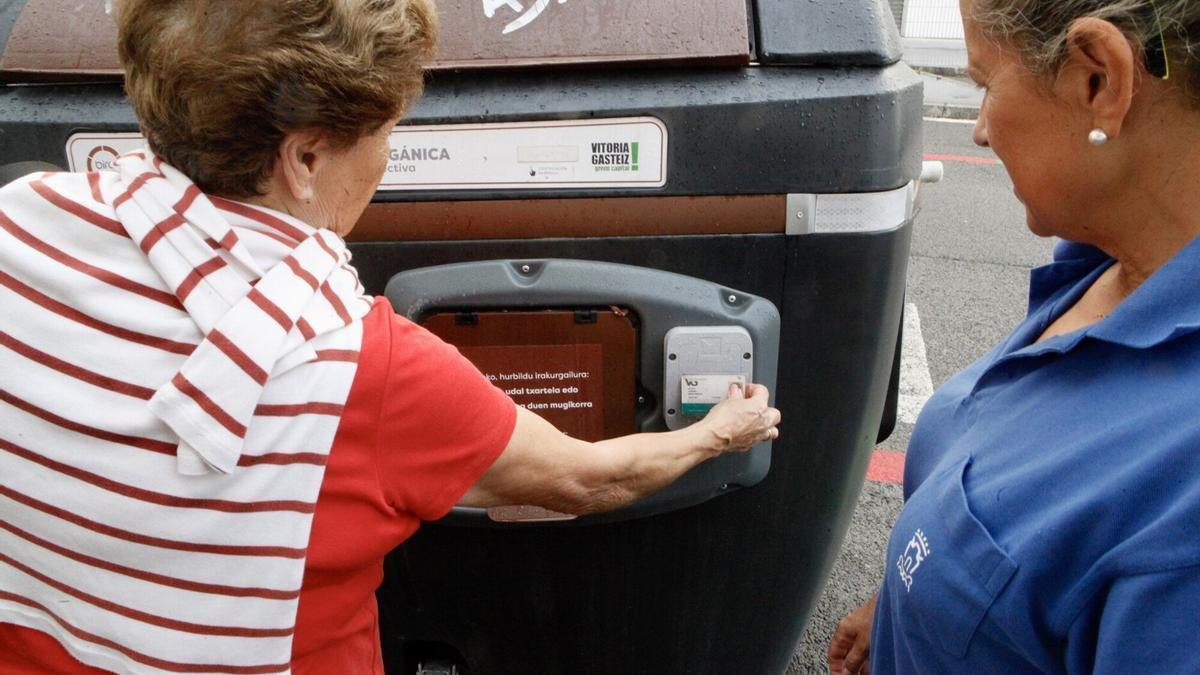 Una mujer abre el contenedor marrón con su tarjeta municipal ciudadana.