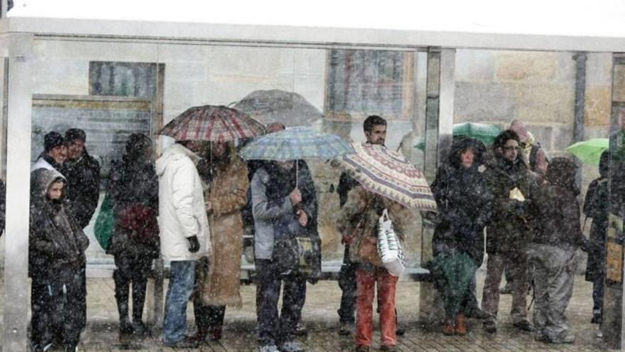 Varias personas esperando a la villavesa en una marquesina.
