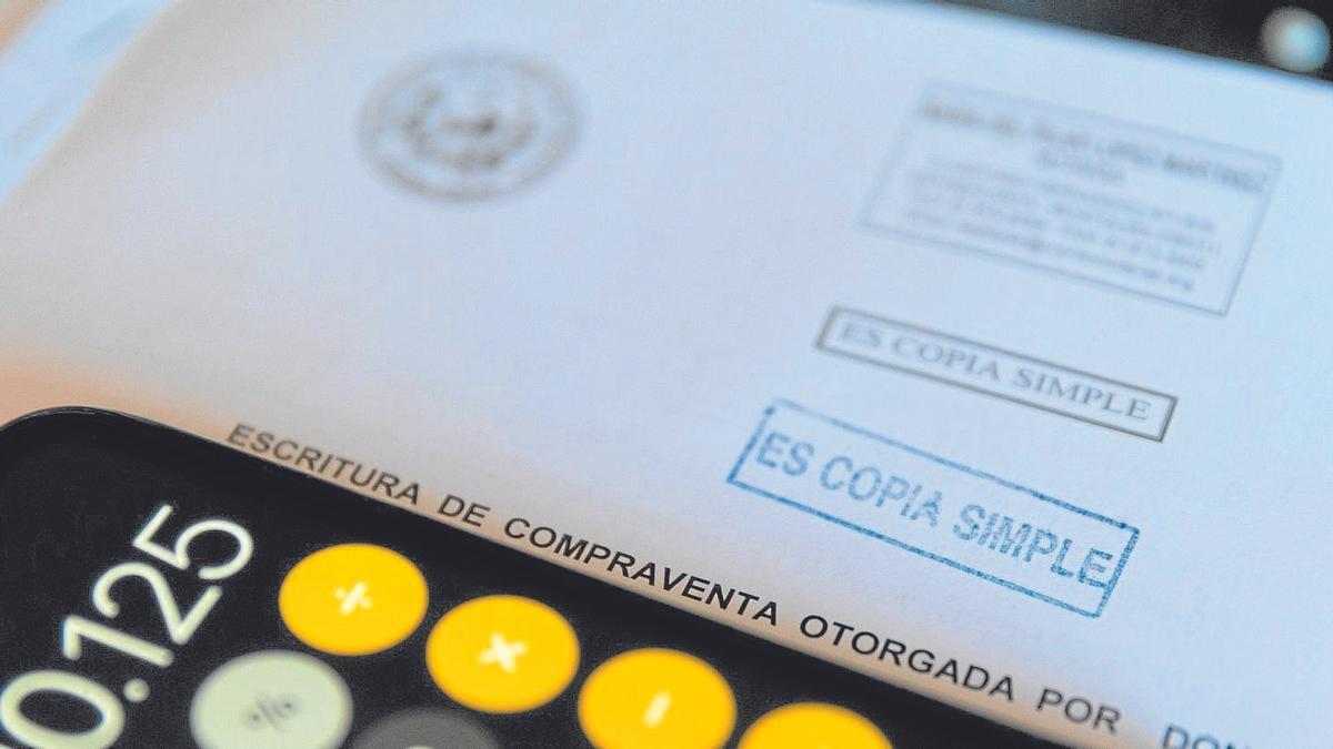 Una calculadora y una escritura de compraventa de una hipoteca.