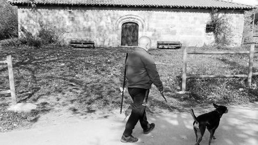 Un hombre pasea con su perro por la ermita de San Juan.