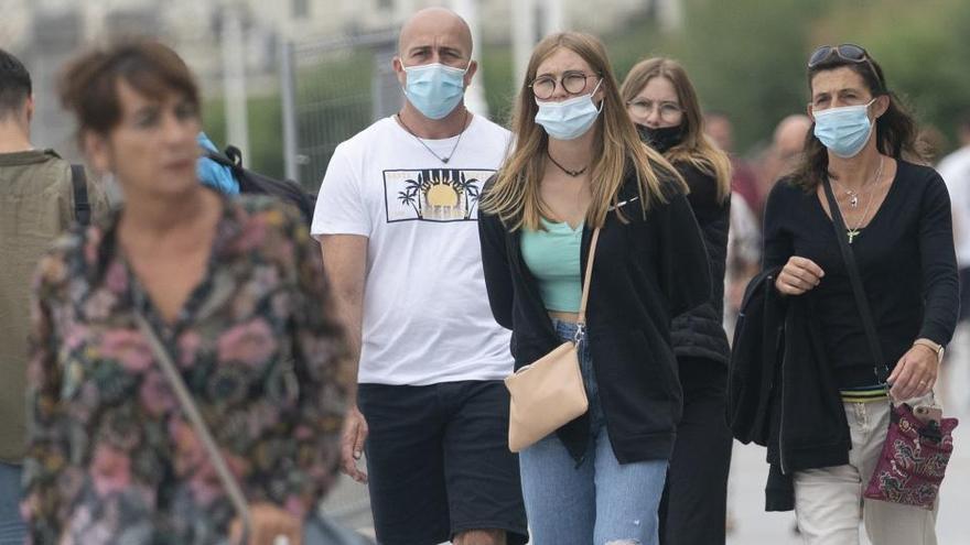 Varias personas pasean protegidas por mascarillas.