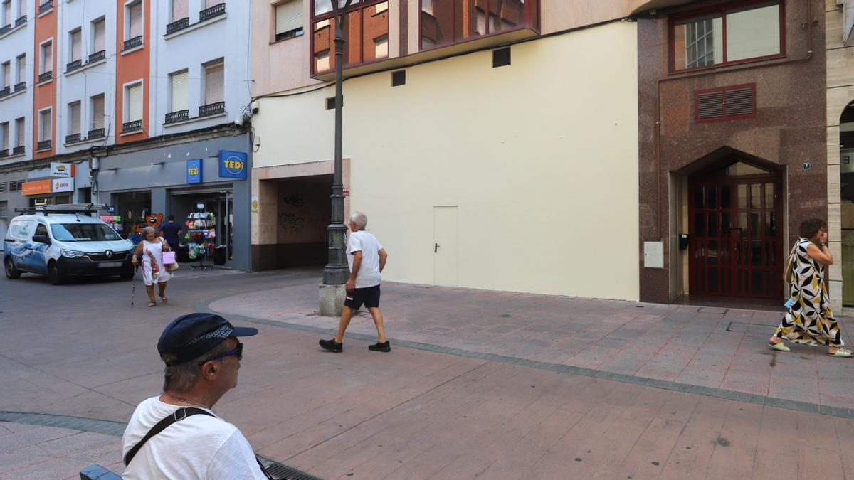 Un hombre sentado en un banco ante la pared en la que antes se encontraba el mural en homenaje a Nevenka en Ponferrada.