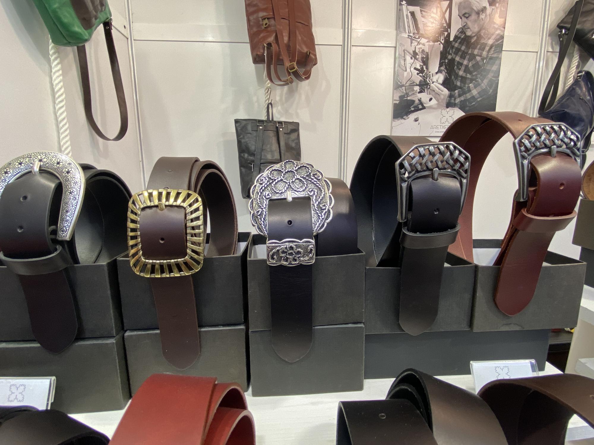 Cinturones artesanos de cuero expuestos en un stand.