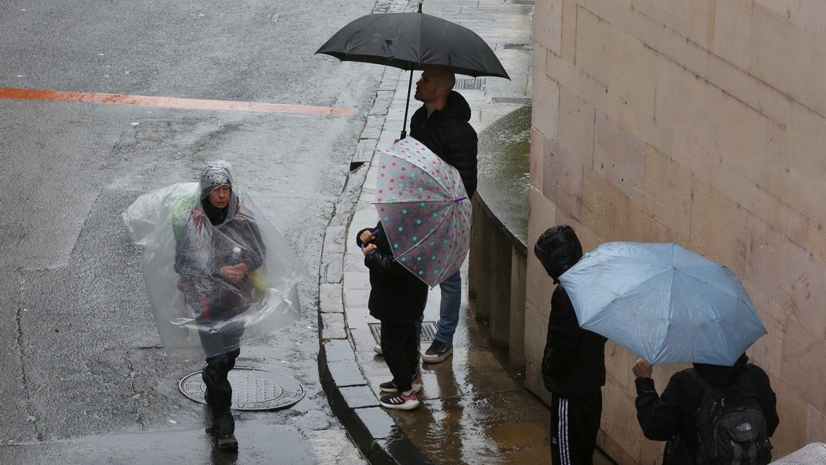 Personas caminan bajo la lluvia en Pamplona.
