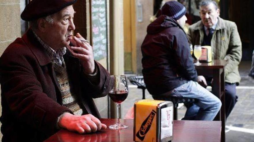 Un hombre fuma un cigarro en la terraza de un bar.