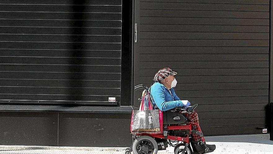 Una persona en silla de ruedas circula por Pamplona protegido con una mascarilla. Foto: Iñaki Porto