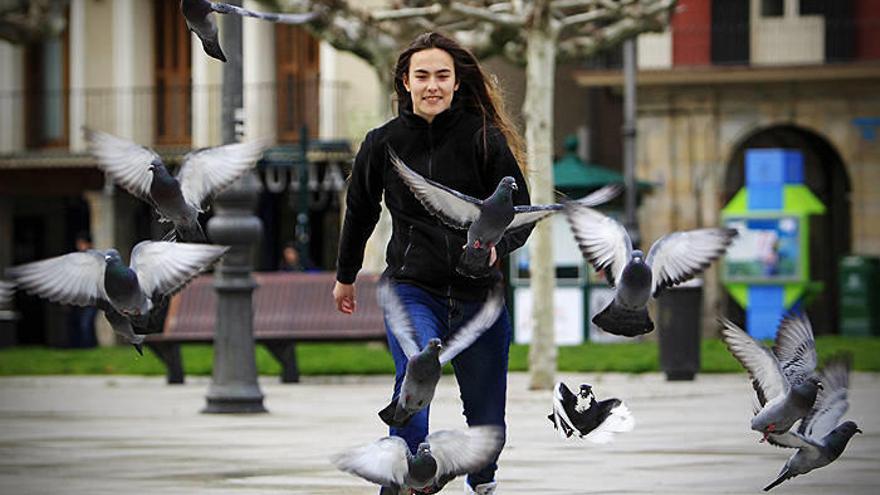 La futbolista del Lagunak Maider España espanta un puñado de palomas en la plaza del Castillo.