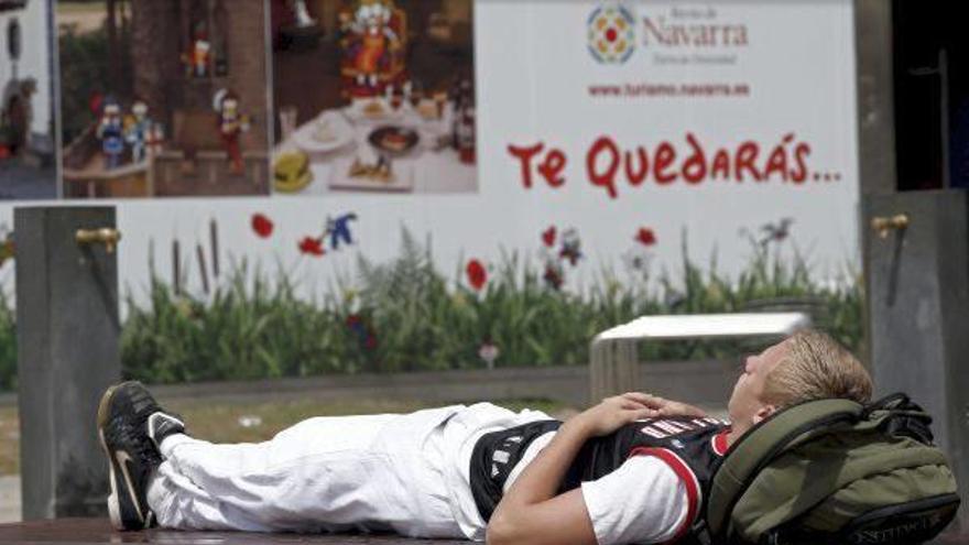 Un turista echa una &#039;cabezadita&#039; en un banco de la plaza del Castillo antes de volver a su país.
