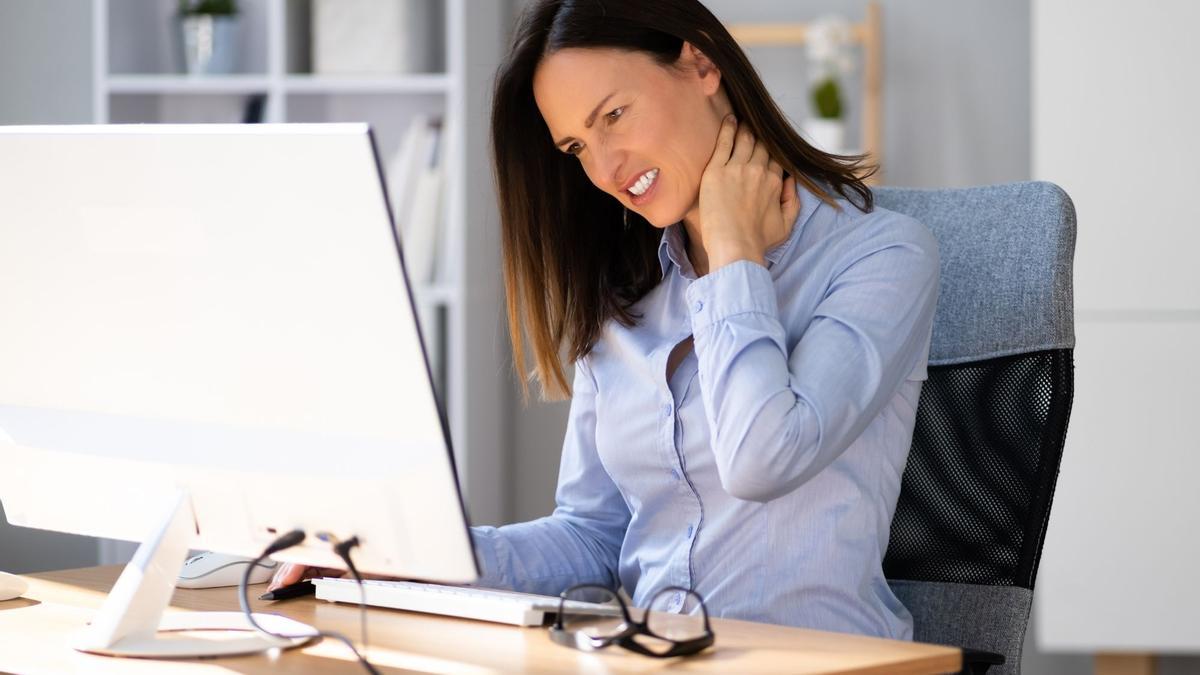 Una mujer se resiente de dolor de cervicales en el trabajo