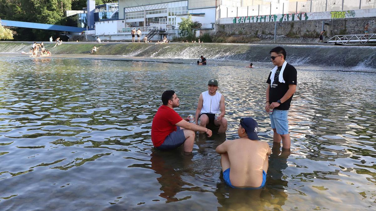 Un grupo de jóvenes refrescándose en el Arga este lunes.