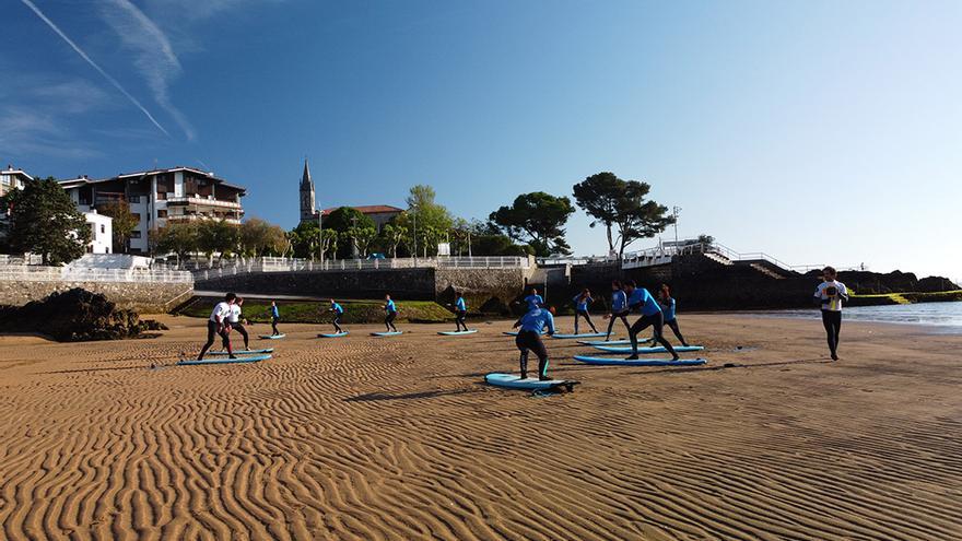 Alumnos practicando ejercicios en la arena antes de entrar al mar.