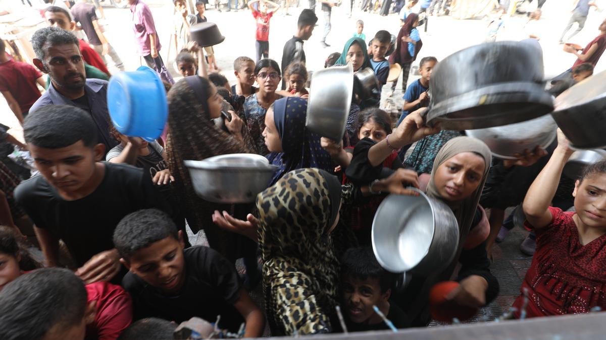 Palestinos esperan recibir comida de un comedor social en medio de una crisis de hambre.