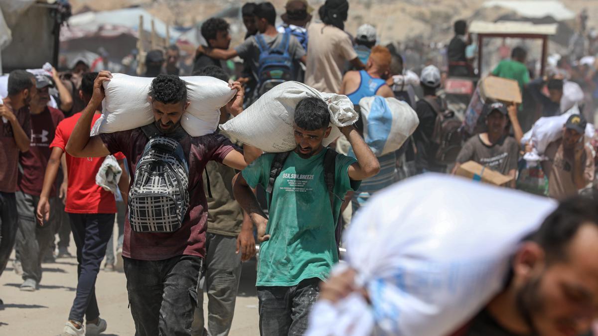 Los palestinos llevan bolsas de harina que obtuvieron de camiones de ayuda que ingresaron a Gaza.
