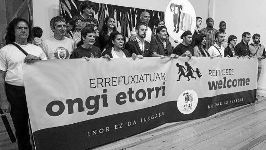 Diferentes asociaciones colaboradoras sostienen la pancarta de bienvenida a los refugiados.