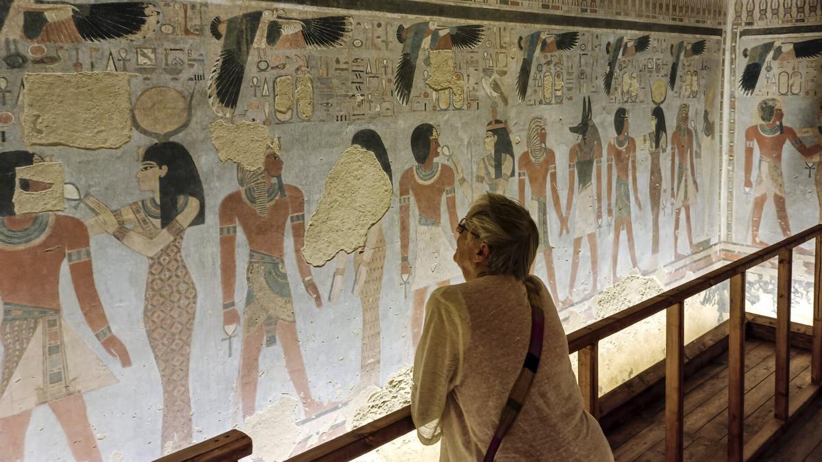 Un turista observa antiguos dibujos faraónicos en el interior de la recién inaugurada tumba del faraón Amenhotep III en Luxor, Egipto.