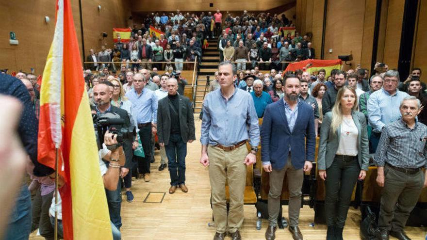 El presidente de Vox, Santiago Abascal, y el secretario general de la formación, Javier Ortega Smith, entre otros, escuchan firmes el himno de España.