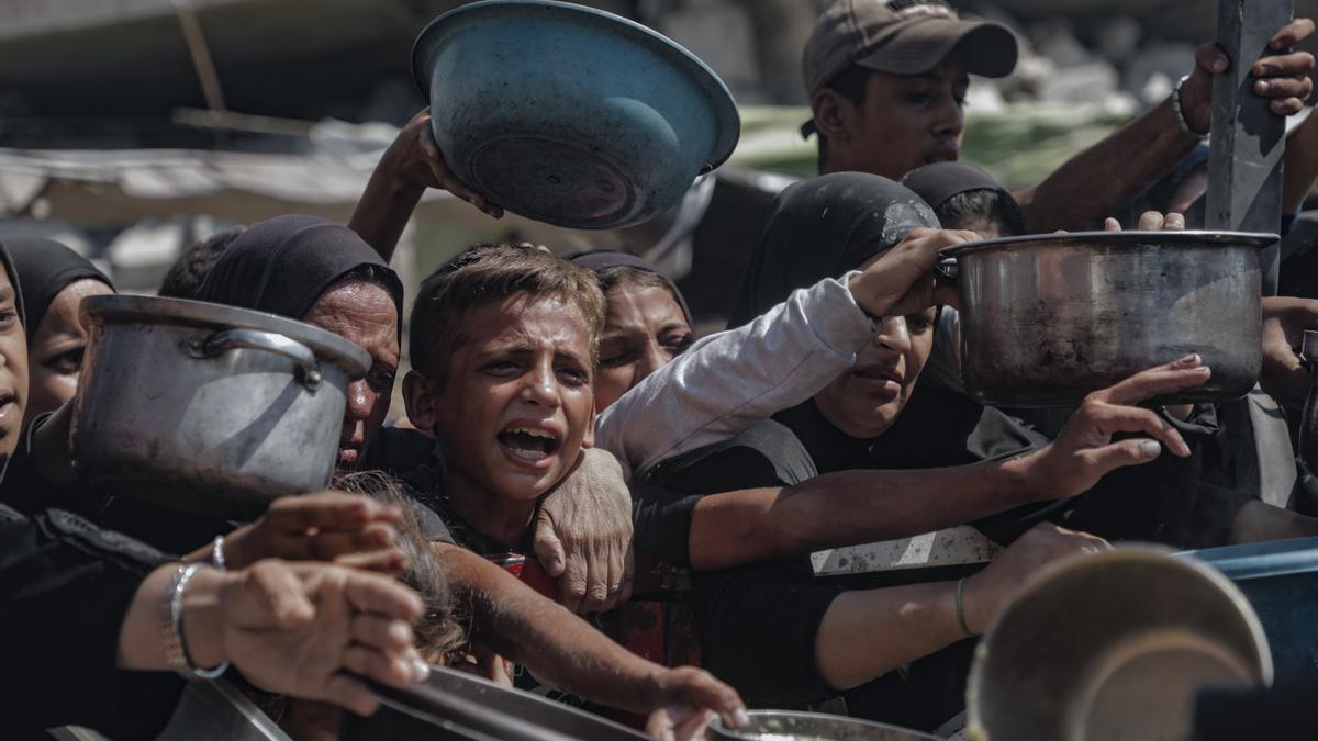 Fotografía tomada el 20 de julio en la ciudad de Gaza, que muestra a niños tratando de conseguir comida en los centros de distribución de ayuda humanitaria.