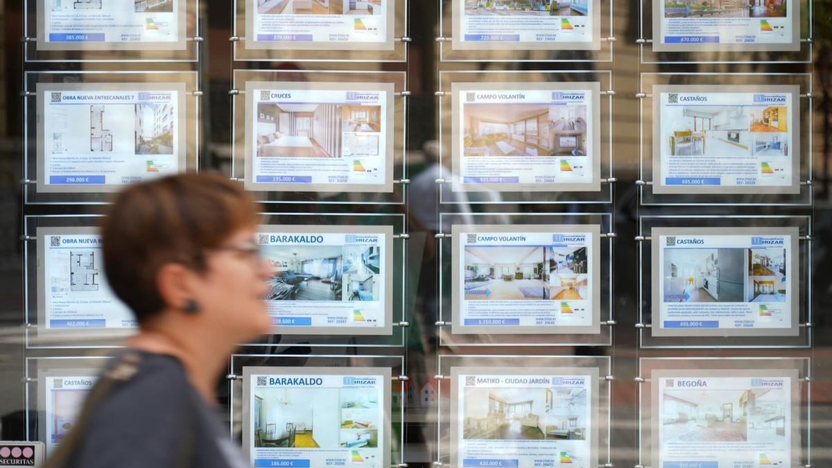 Una mujer pasa frente al escaparate de una inmobiliaria de Bilbao.