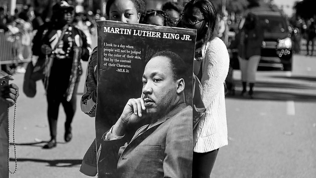Una mujer sujeta un poster de Martin Luther King Jr