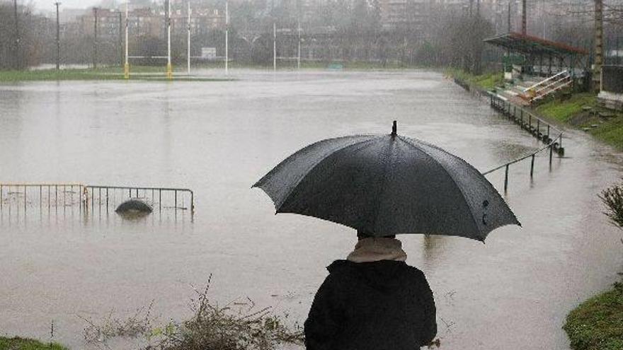 Un hombre observa las instalaciones deportivas de Landare, en Hernani, anegadas tras desbordarse el río Urumea.