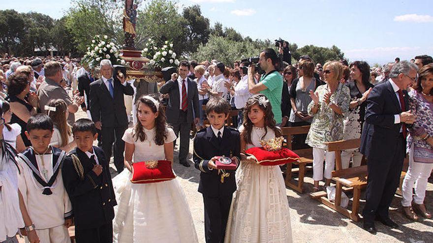 Varios niños portan las coronas mientras otros vecinos llevan la imagen de la Virgen.