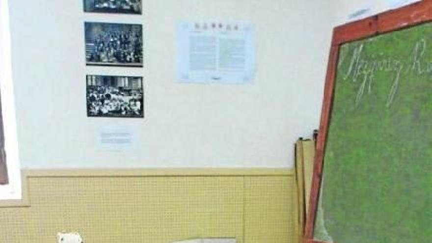 La mesa del maestro llena de cuadernos. Al fondo, un homenaje a las maestras.