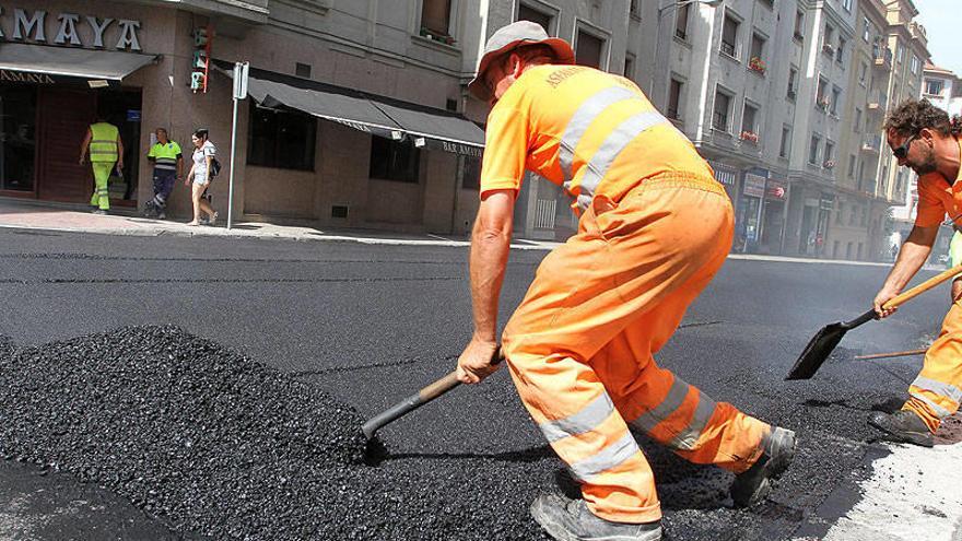 Un trabajador fuerza su espalda durante el asfaltado de una calle.