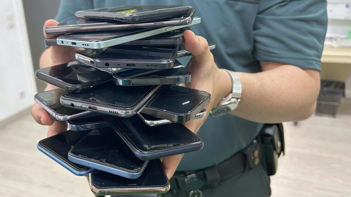 Un agente de la Guardia Civil sostiene varios teléfonos móviles en una imagen de archivo