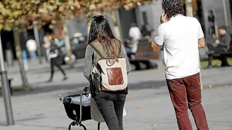 Una pareja pasea a su hijo en un carrito por la calle. Foto: Iban Aguinaga