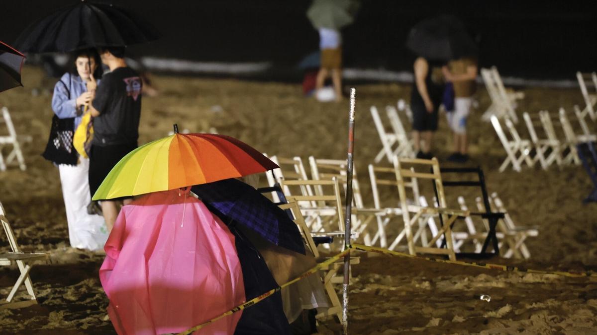 Personas bajo la lluvia durante la noche del martes tras los Fuegos Artificiales