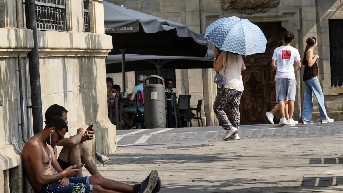 Al fondo, una mujer se protege del sol con un paraguas este pasado domingo en Pamplona.