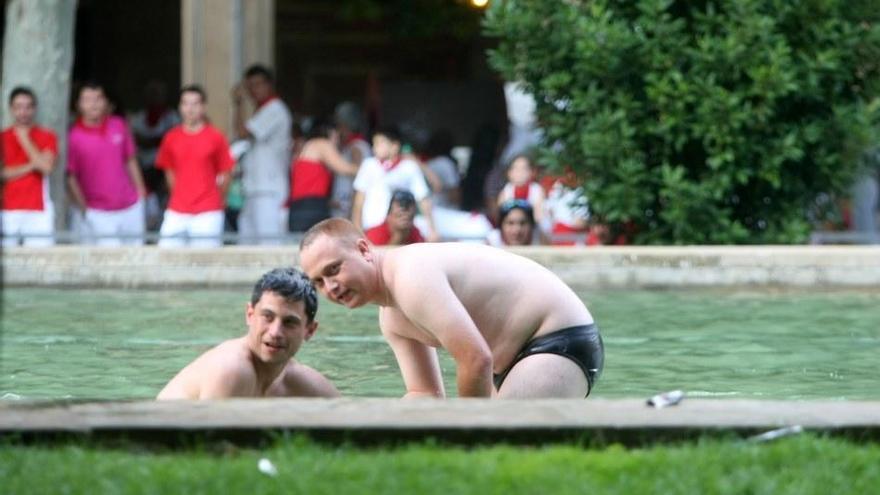 Dos jóvenes se bañan en una fuente.