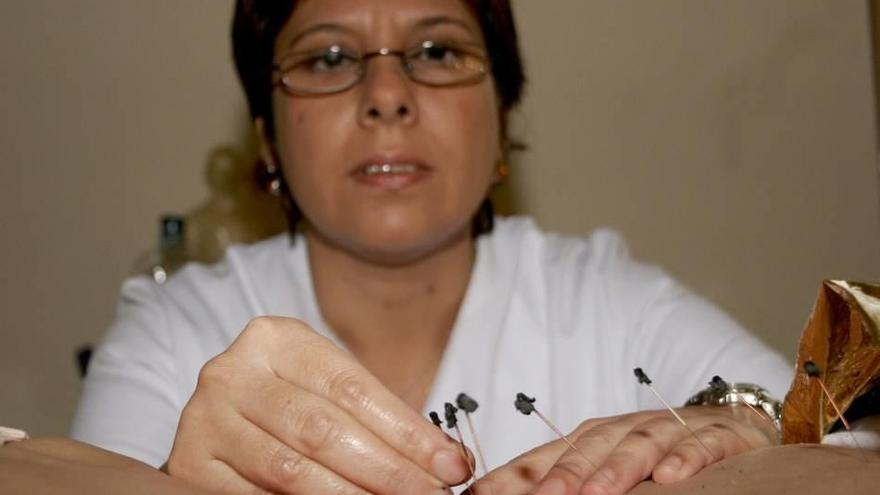 Una mujer coloca agujas de acupuntura.