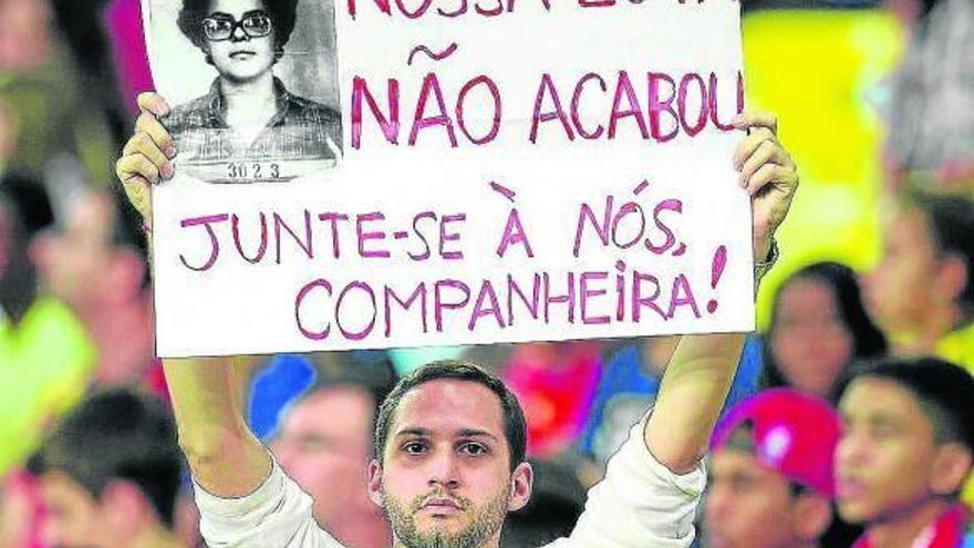 Un manifestante, con la foto de Dilma Rousseff en su ficha policial, le pide que se una a las protestas.
