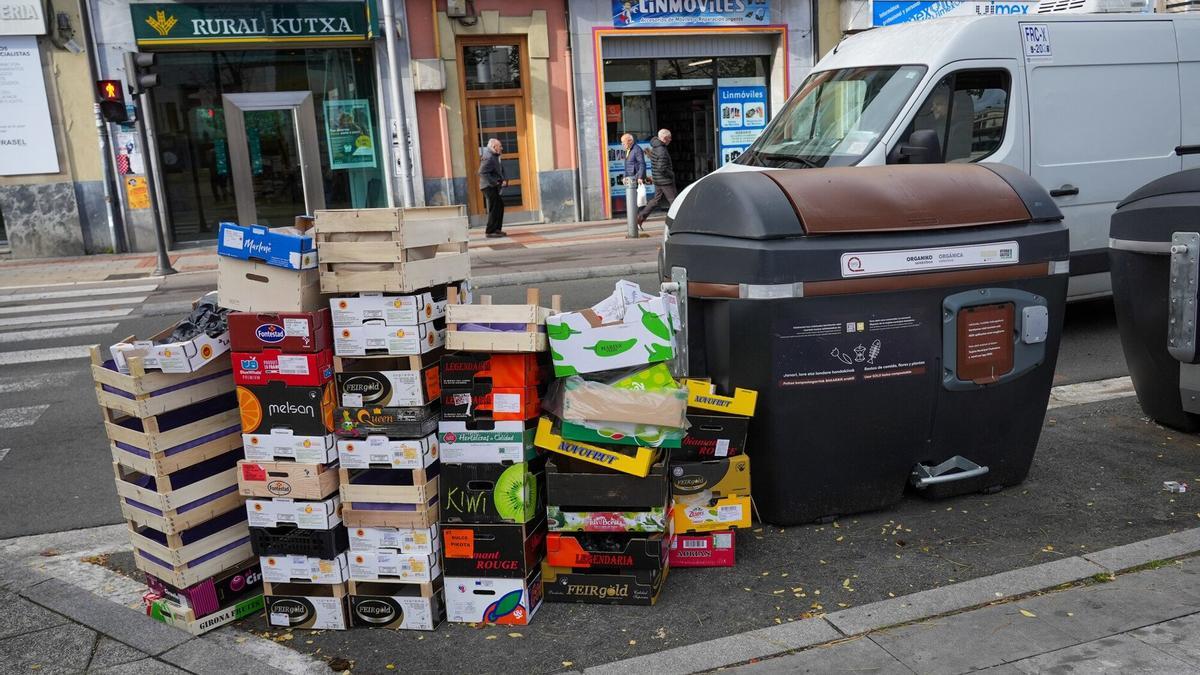 Cajas de cartón apiladas al lado de un contenedor marrón en Vitoria.