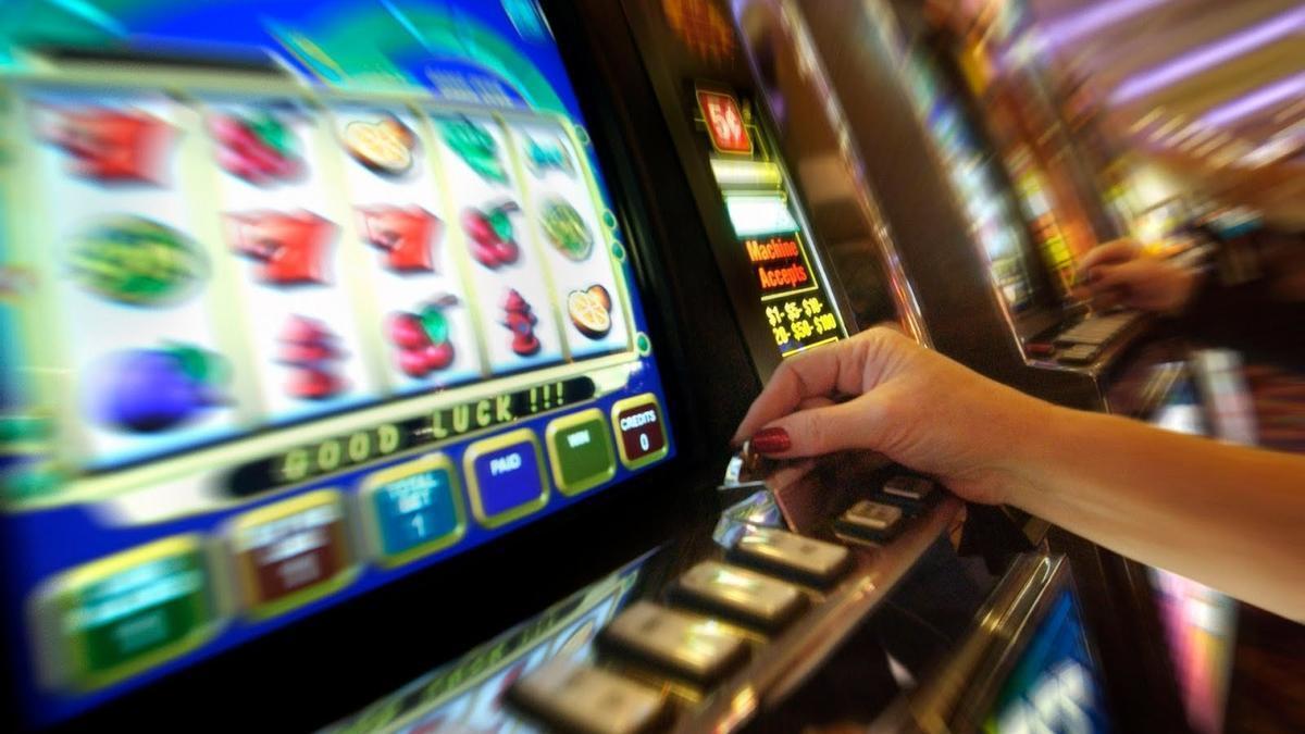 Una mujer juega en una máquina tragaperras. Una mujer juega en una máquina tragaperras.